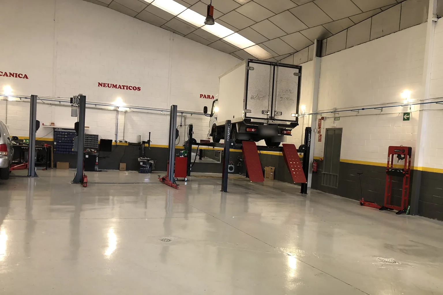 Camión ligero de caja subido al elevador de cuatro columnas en la nave del taller