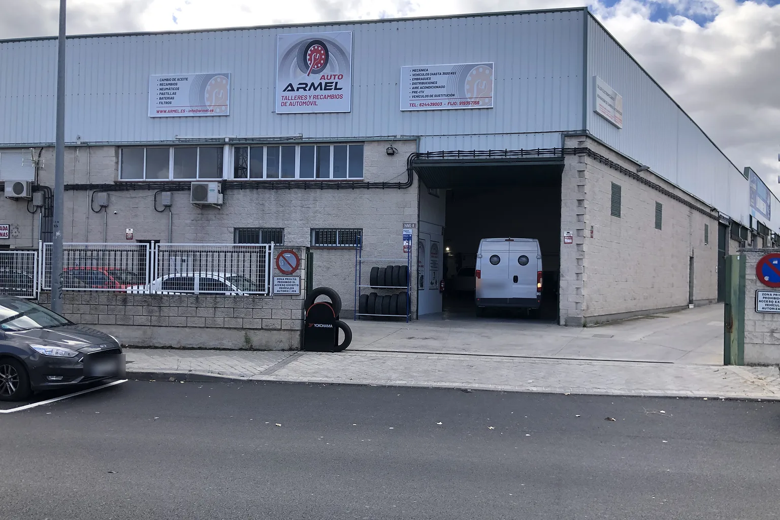 Fachada de la nave de Auto Armel en Leganés, con el rótulo del taller y el portón abierto