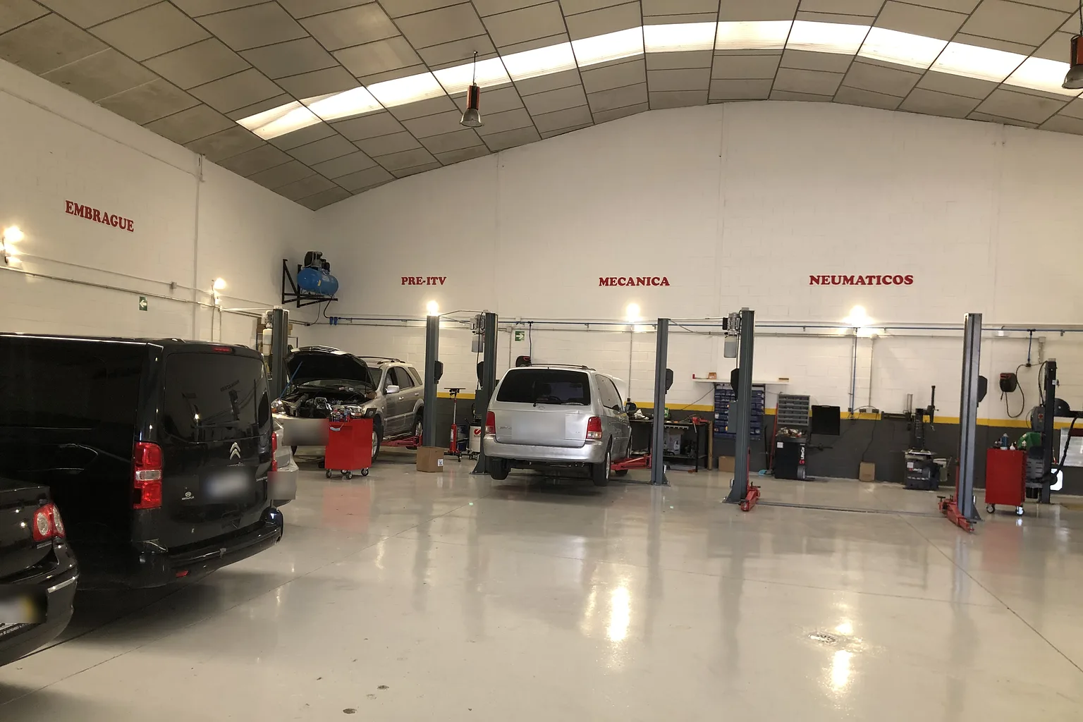 Interior de la nave de Auto Armel con varios elevadores y coches en reparación